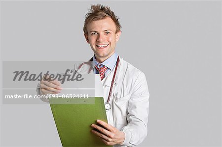 Portrait of a happy male doctor holding a clipboard over gray background