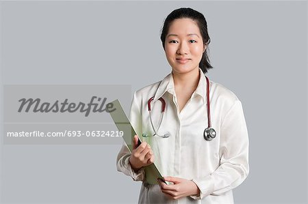Portrait d'une jeune femme médecin asiatique avec un presse-papiers sur fond gris