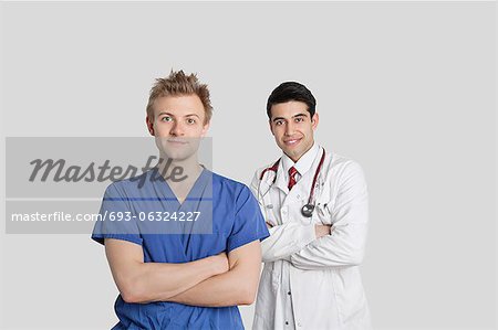 Portrait of male nurse and doctor standing with arms crossed over gray background