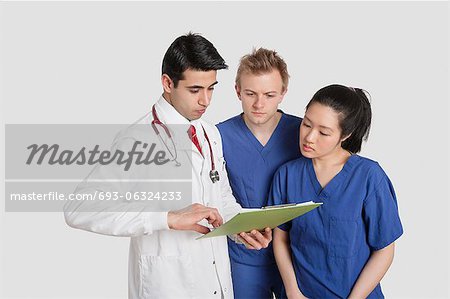 Three healthcare professional discussing medical report over gray background