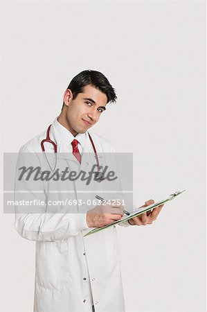 Portrait of an Indian male doctor writing prescription over light gray background