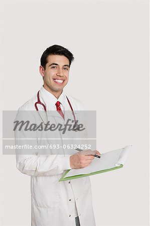 Portrait of a cheerful Indian male doctor holding a medical chart over light gray background