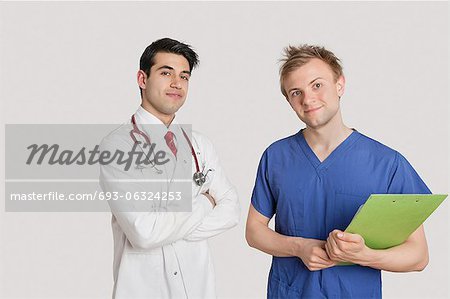 Portrait of doctor standing with coworker over light gray background