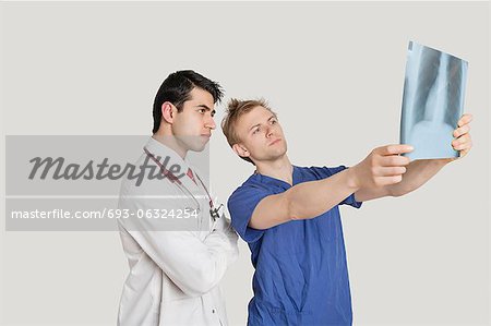 Medical professionals looking at chest x-ray over light gray background