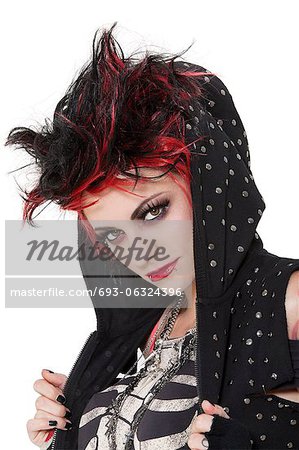 Close-up portrait of young punk woman wearing hood over white background