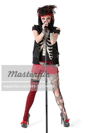 Portrait of female punk rock musician with microphone over white background