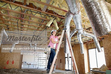 Young woman climbing up the ladder while looking at ceiling