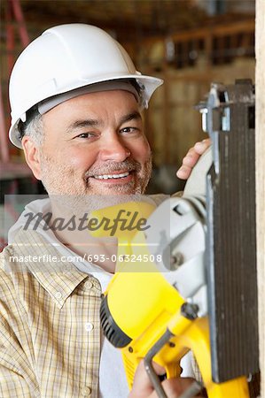 Porträt einer lächelnd männliche Arbeitnehmer schneiden Bauholz mit einer Kreissäge