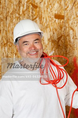 Portrait de sourire mâle ouvrier avec un fil électrique rouge