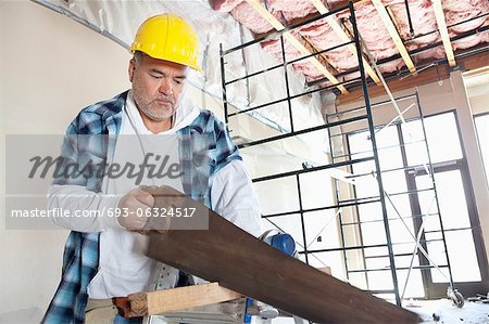 Construction hommes sérieux travailleur coupait du bois avec une scie à main