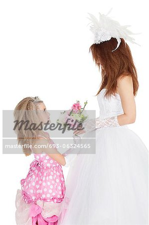 Side view of bride and bridesmaid looking at each other while holding bouquet over white background