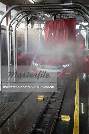 Vehicle on conveyor belt moving through car wash process