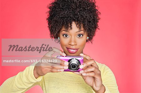 Portrait of an African American woman holding a camera over colored background