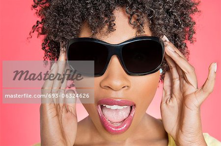 Gros plan d'une femme afro-américaine, lunettes de soleil sur fond coloré