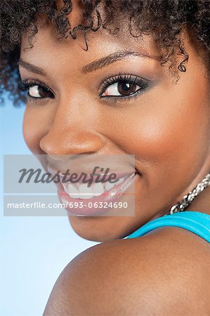 Close-up portrait of an African American woman looking back over colored background