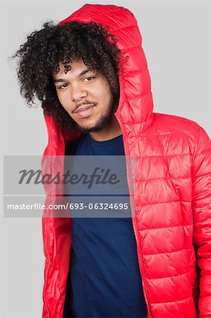 Portrait de jeune homme vêtu d'une veste rouge avec capuche sur fond coloré