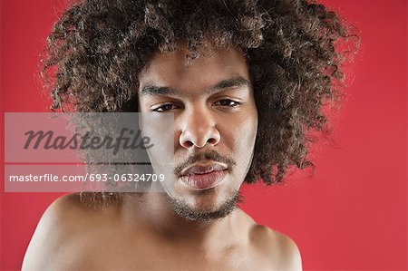 Close-up portrait of a young man with curly hair over colored background