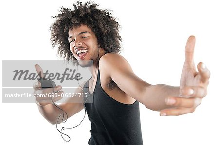 Portrait d'un jeune homme heureux en gilet dansant à tunes de lecteur mp3 sur fond blanc Portrait d'un jeune homme heureux en gilet dansant à tunes de lecteur mp3 sur fond blanc