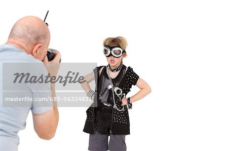 Senior adult photographer shooting punk kid over white background