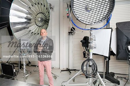 Photographe senior avec caméra et réflecteurs de lumière en studio