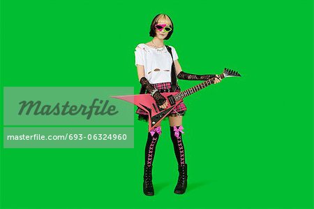 Punk woman with guitar over green colored background
