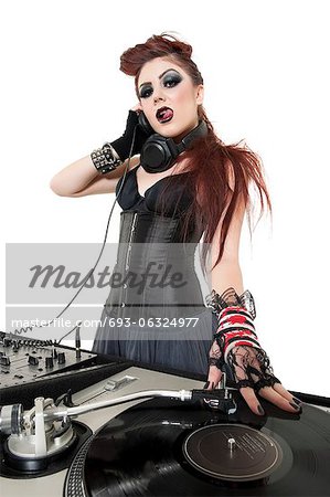 Portrait of beautiful punk DJ with sound mixing equipment over white background