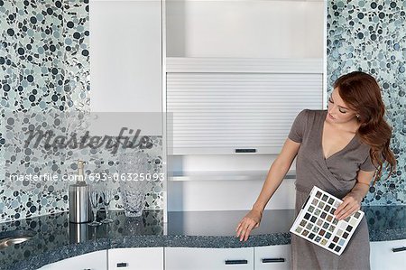 Beautiful young woman with color samples looking at contemporary kitchen cabinets Beautiful young woman with color samples looking at contemporary kitchen cabinets