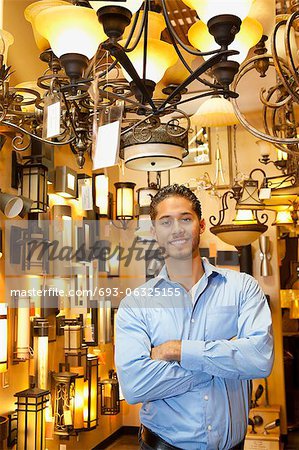 Portrait of happy handsome man standing with arms crossed in store