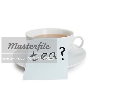 Close-up of sticky notepaper with teacup over white background