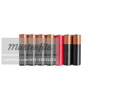 Red amid black batteries over white background