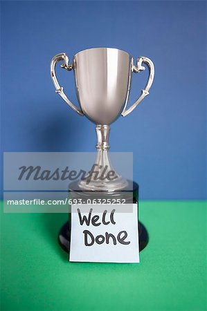 Winning trophy award with sticky note over colored background