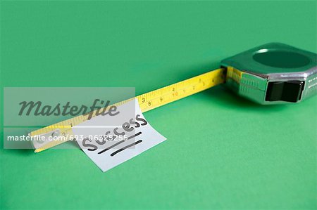 Close-up of sticky note stuck to measuring tape over colored background