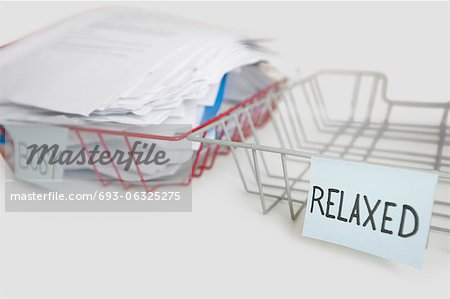 Stack of paperwork in busy tray with empty relaxed platter over white background