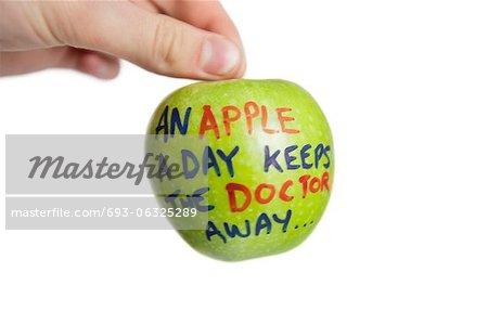 Cropped image of hand holding a granny smith apple with sayings text over white background