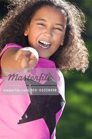 Portrait of a beautiful young happy mixed race interracial African American girl pointing, shot outside in summer sunshine