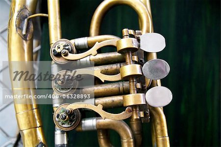 Old brass instrument  with three valves hanging on the wall