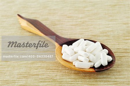 The pills on ladle spoon made from wood.