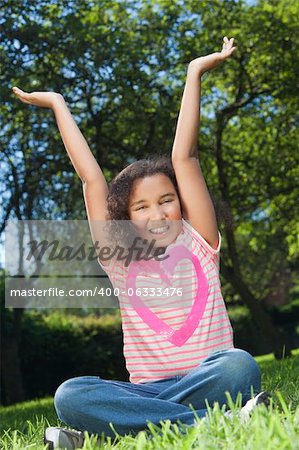 Portrait photograph of a beautiful young smiling happy mixed race interracial African American girl, shot outside in a park with her arms in the air