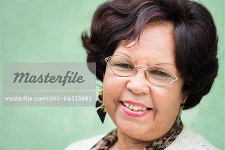 Portrait of happy old african american woman with glasses and wig smiling at camera