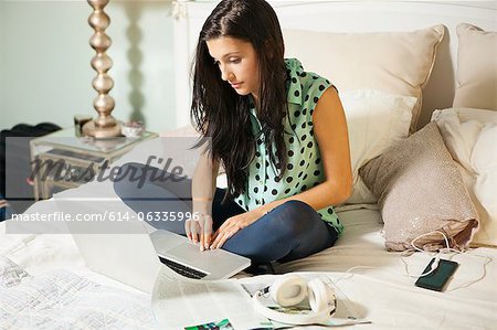 Young woman on bed with laptop