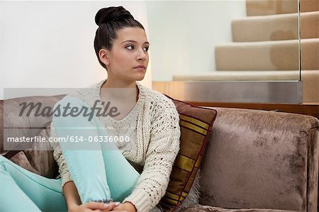 Nachdenkliche junge Frau auf dem sofa
