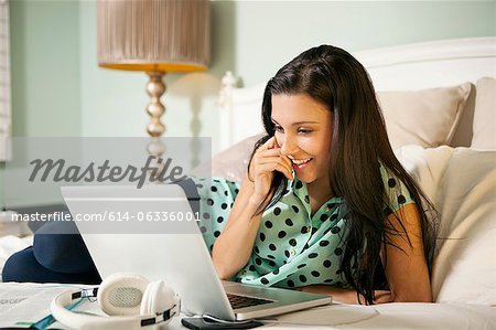 Jeune femme au lit avec ordinateur portable