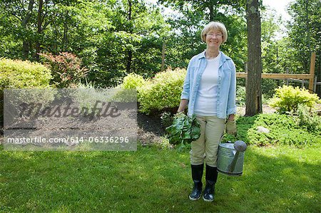 Woman with watering can and beetroot in garden