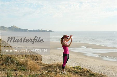 Aktive junge Frau nehmen Foto am Strand