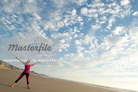 Jeune femme sur la plage avec les bras tendus