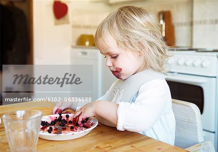Little girl eating fruits in kitchen
