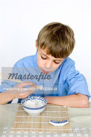 Portrait de garçon de manger du riz avec des baguettes