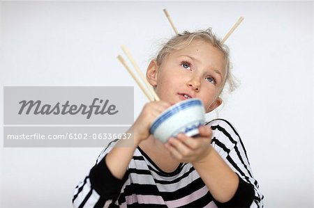 Fille avec chignon manger avec des baguettes