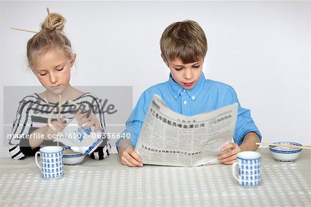 Girl pouring tea and boy reading newspaper