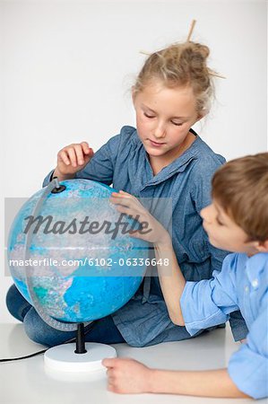 Boy and girl reading globe